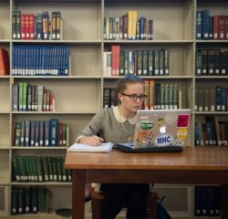 student-on-laptop-in-library.jpg A student working in the library with a notebook and a laptop