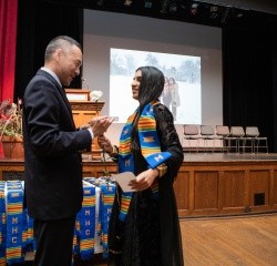 Calvin Chen presenting a student with a stole during the stoling ceremony