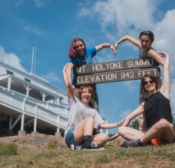 Students making a heart shape with their arms around the Mt. Holyoke state park sign. Mountain Day 2024. Photo by Max Wilhelm.
