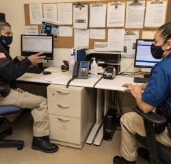 Two public safety officers seated at desks having a discussion