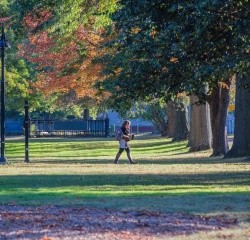 A student walking on campus in the fall