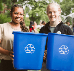 Two students, each holding a blue recycle bin