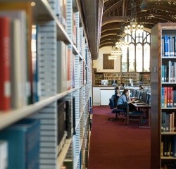 Two students working at a long table in the library.
