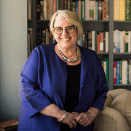 Sonya Stephens standing by a window, a book case behind her.