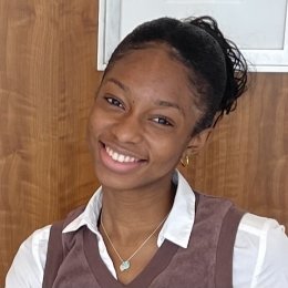 Sarah Bell ’25, wearing a white shirt and brown vest, smiles at the camera