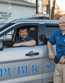 Public Safety &amp; Service staff sitting in and standing next to a public safety vehicle