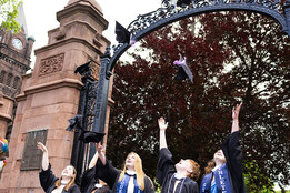 Mount Holyoke Commencement 2024 - Graduating students toss their caps in the air in front of the gates