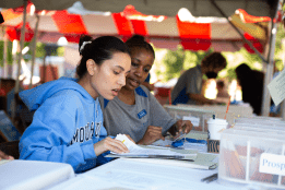 Students reviewing paperwork in the welcome tent during move-in day 2022