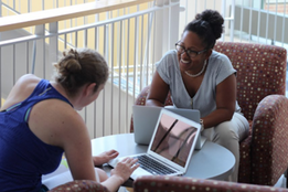 Two students in the graduate program discuss strategy while sitting together in Kendade.