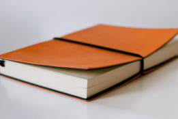 An orange notebook with an elastic holding the cover closed