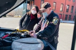 A student learning some vehicle maintence tips from a public safety officer
