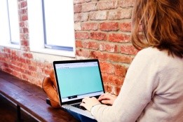 A student sitting on a bench working on a laptop