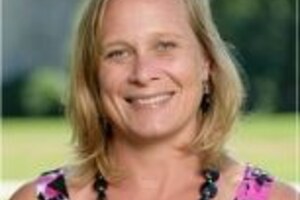 Amanda Mayfield, a woman with short blond hair wearing a black necklace and a pink and black top.