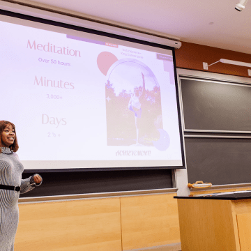 A student presenting in front of a screen during LEAP Symposium 2022