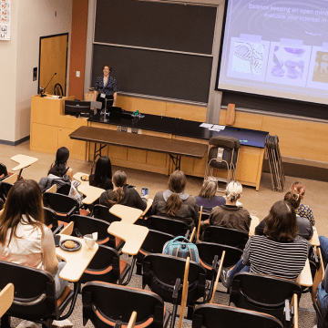 A student presents in front of a lecture hall audience during LEAP Symposium 2022