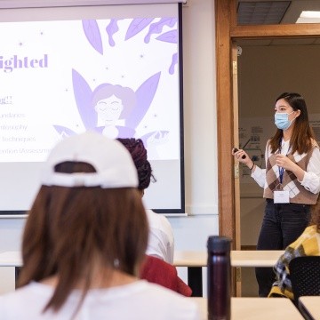 A student standing next to a presentation screen while giving a presentation during LEAP Symposium 2022