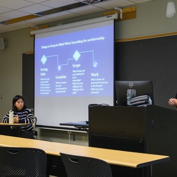 LEAP Presenter in front of a podium, with a screen presentation on the side. LEAP 2024, Mount Holyoke College