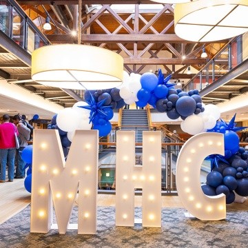 White letters MHC with lights, and blue balloons in the Community center for Experience MHC! April 5, 2025, Photo by Jo Chattman.
