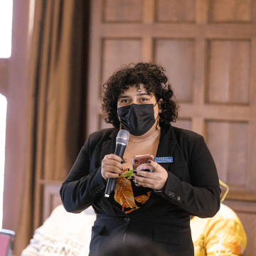 A member of the audience standing to ask a question during a session of the 2023 BOOM! Learning Symposium