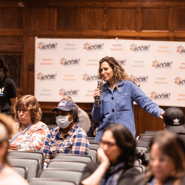 Two members of the audience standing to ask questions during the 2023 Boom! Learning Symposium