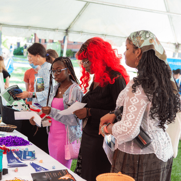Students asking questions at an information table in the welcome tent during move-in day 2022