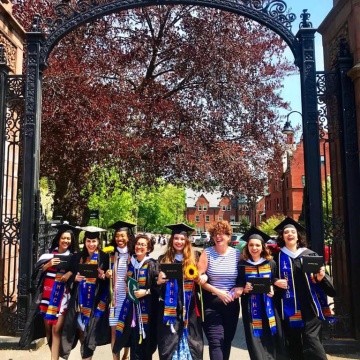 Posse students in graduation regalia pose by the Gates.