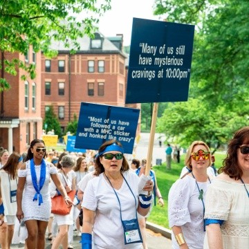 A blue pegasus class marches in the Laurel Parade, one of whom is holding a sign that says &quot;Many of us still have mysterious cravings at 10pm&quot;