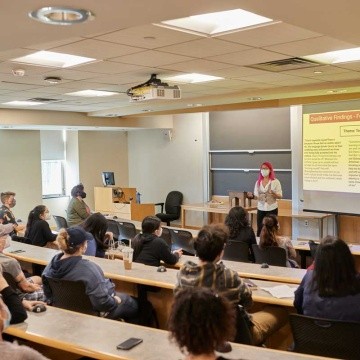 A student presenting in front of a lecture hall during Senior Symposium