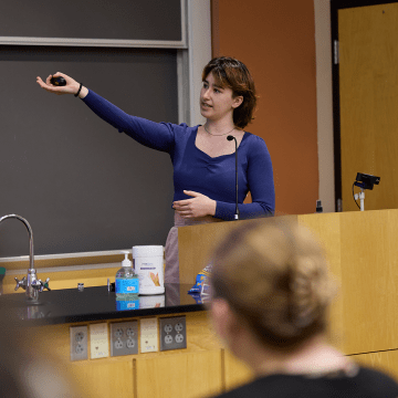 A student jestering at the blackboard during Senior Symposium 2023