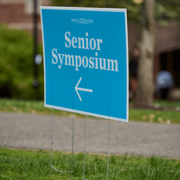 A lawn sign advertising Senior Symposium