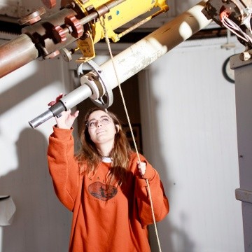 A student poses with the telescope in the obseervatory