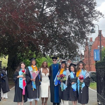Posse scholars pose in regalia, some holding flowers.