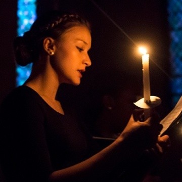 A singer uses candlelight to view music during a Vespers concert