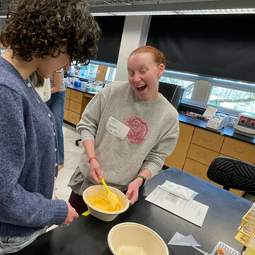 QIC students mix their yellow slime ingredients together.