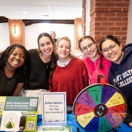 Mount Holyoke College experience - students smiling with sustainability information in front of them