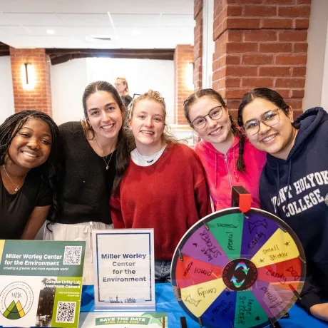 Mount Holyoke College student experience - students smiling with sustainability information in front of them