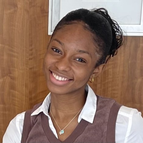 Sarah Bell ’25, wearing a white shirt and brown vest, smiles at the camera