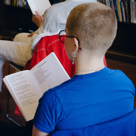 A person in an audience looking at a book.
