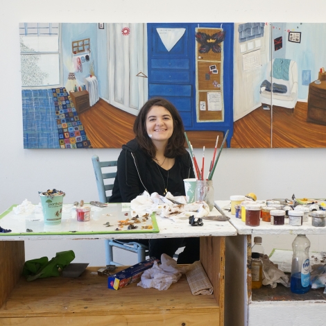 Anna Berlin ’15 sitting at a desk surrounded by art. 