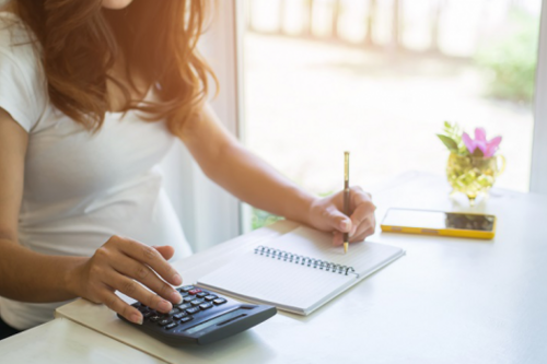 A person at a desk with a notepad and a calculator