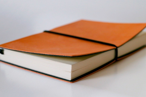 An orange notebook with an elastic holding the cover closed