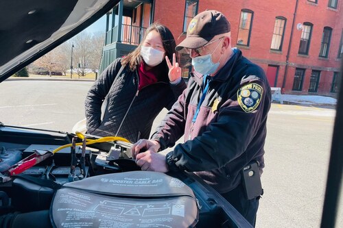 A student learning some vehicle maintence tips from a public safety officer