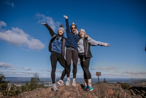 Three students cheering atop Mount Holyoke