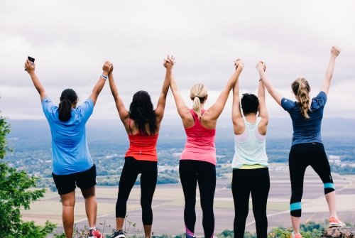 Students holding hands above their heads atop the mountain on Mountain Day