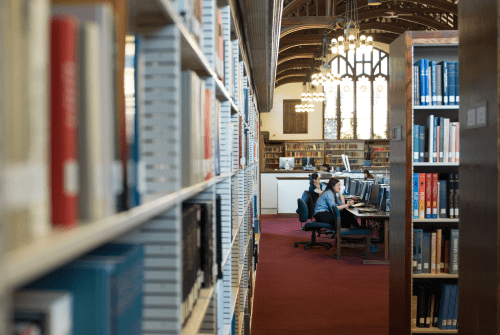 Two students working at a long table in the library.