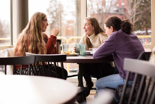 Three students at a table in the dining commons