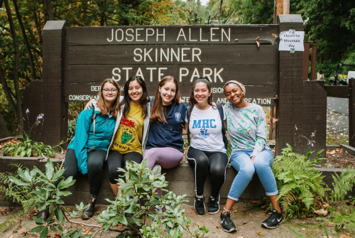 A group of students sitting by the Joseph Allen Skinner State Park sign on Mountain Day