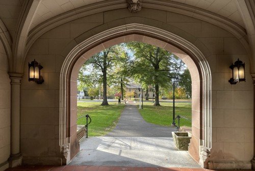 A view from the covered hall front entrance to Mary Woolley, green space and street in view.