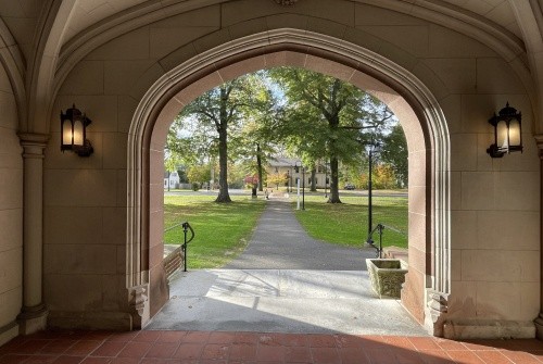 A view from the covered hall front entrance to Mary Woolley, green space and street in view.