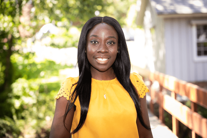 Amanda Awadey - a black woman wearing yellow and smiling - on the Mount Holyoke campus in 2023